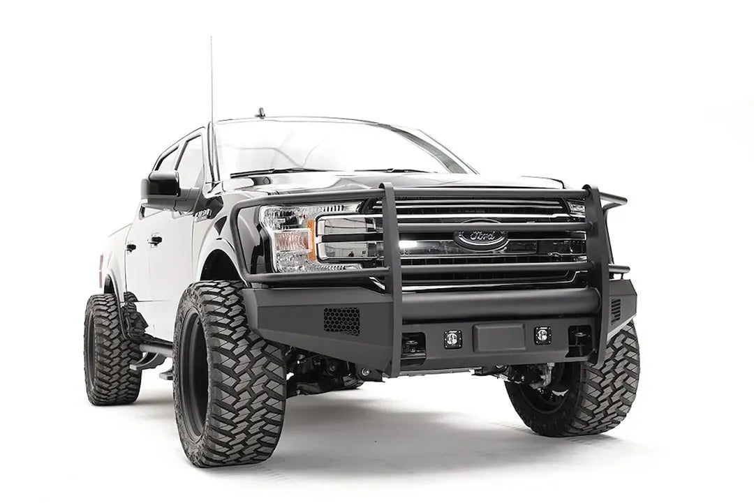 Fab Fours Elite adaptive cruise control relocation bracket on a black Ford F-150, passenger-side front three-quarter view, showing the relocated sensor plate in an Elite bumper with full guard