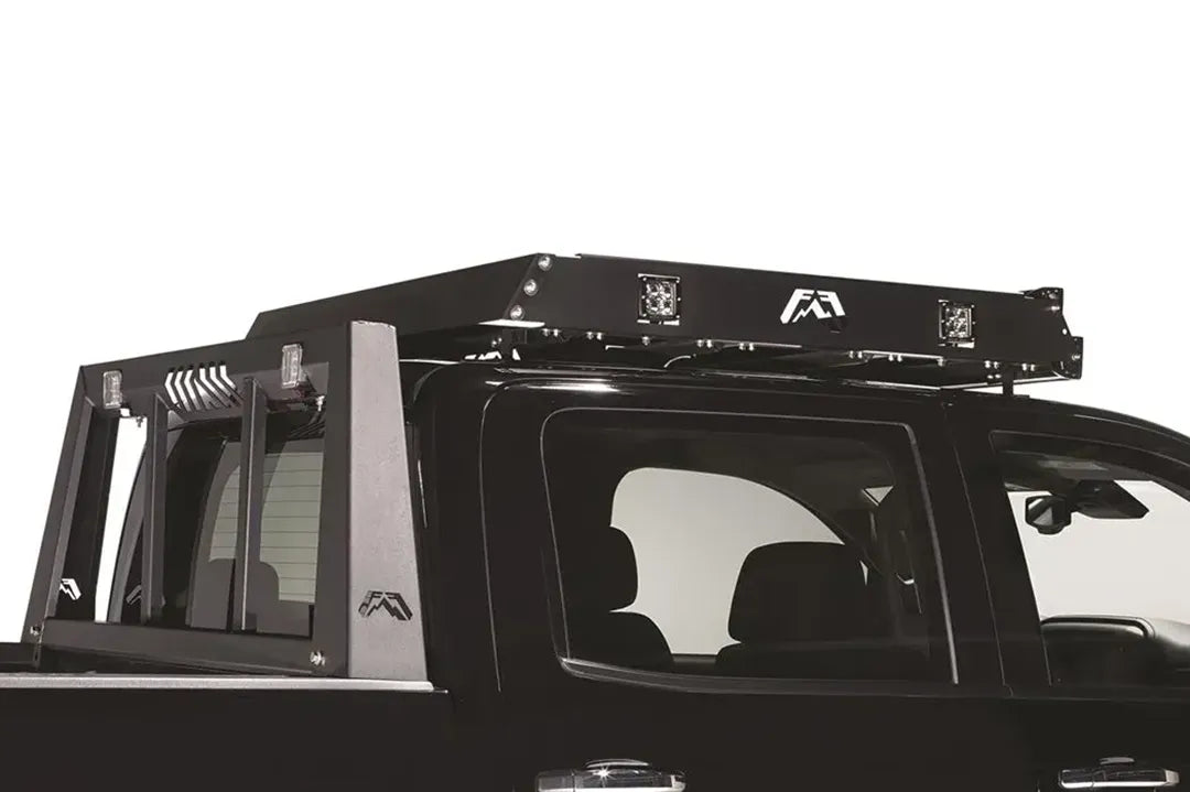 Fab Fours roof rack mounted on a black pickup, close-up view, showing the rack frame, cube lights and logo cutouts