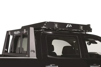 Fab Fours roof rack mounted on a black pickup, close-up view, showing the rack frame, cube lights and logo cutouts