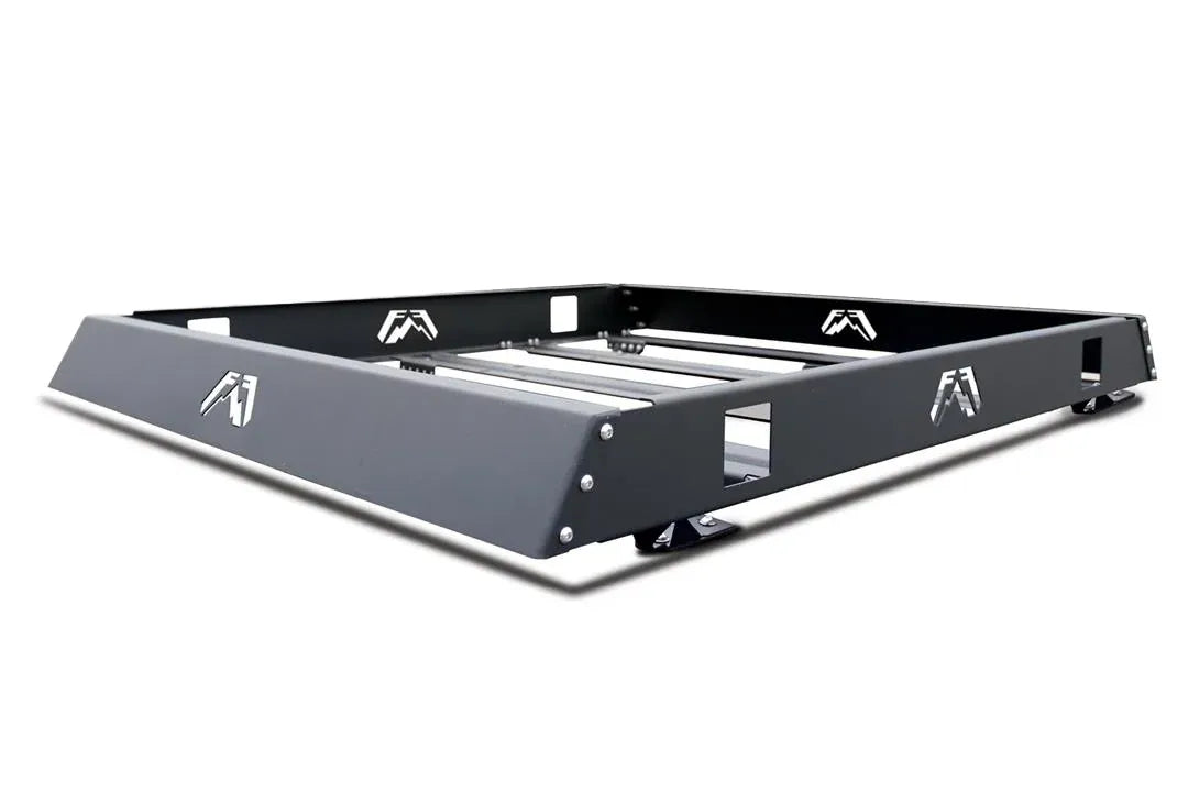 Fab Fours roof rack in black powder coat, angled view, showing the open basket frame, crossbars, logo cutouts and mounting feet
