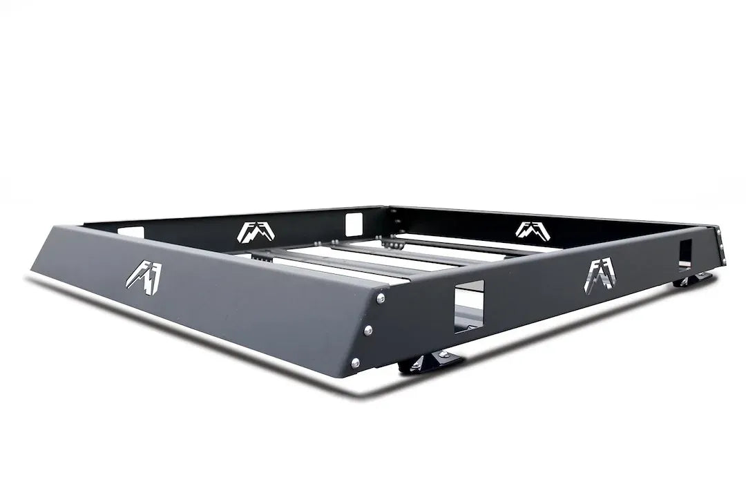 Fab Fours roof rack in black powder coat, angled view, showing the open basket frame, crossbars, logo cutouts and mounting feet