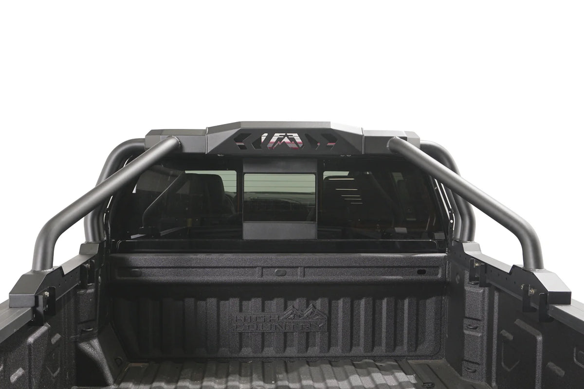 Fab Fours Sport Rack installed in a pickup truck bed, rear view, showing the matte black tubular hoops and center light pod housing with Fab Fours logo cutout behind the cab