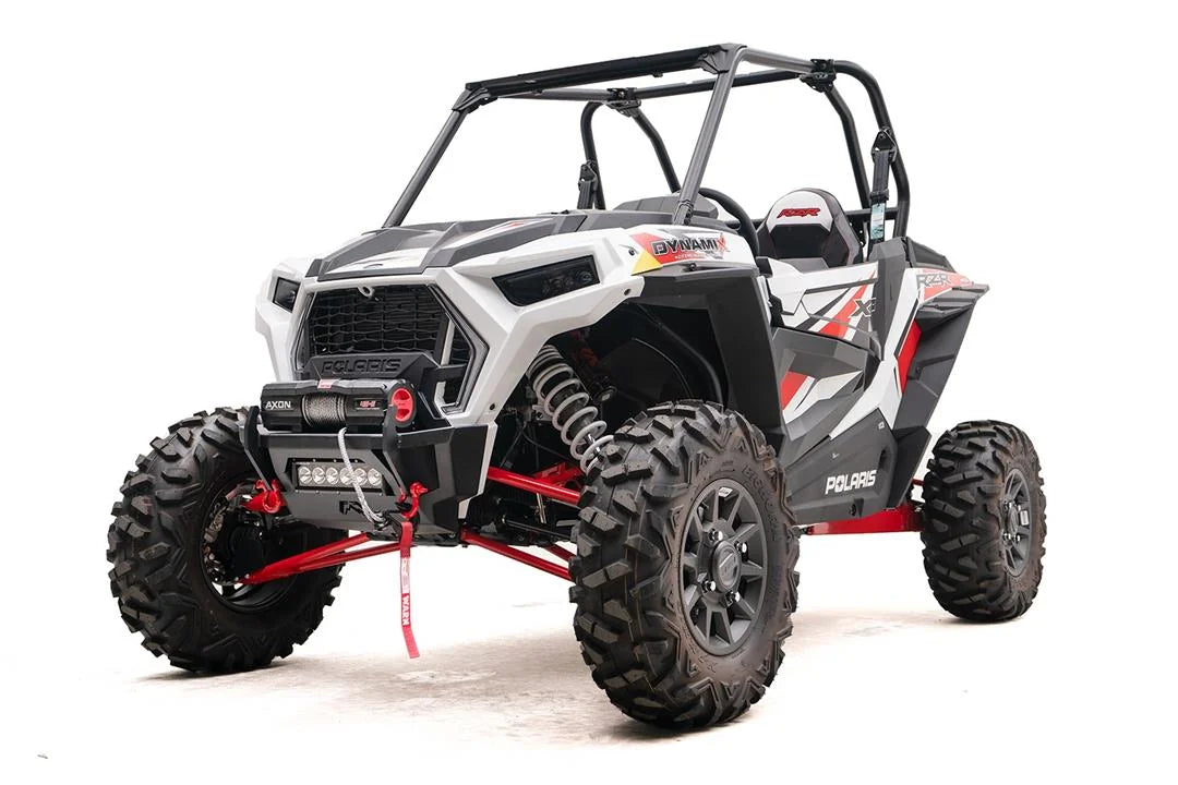 Fab Fours SxS winch bumper on a white Polaris RZR XP, driver-side front three-quarter view, with Warn Axon winch, LED light bar, and red D-ring shackles