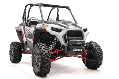 Fab Fours SxS winch bumper on a white Polaris RZR XP, passenger-side front three-quarter view, with Warn Axon winch, LED light bar, and red D-ring shackles
