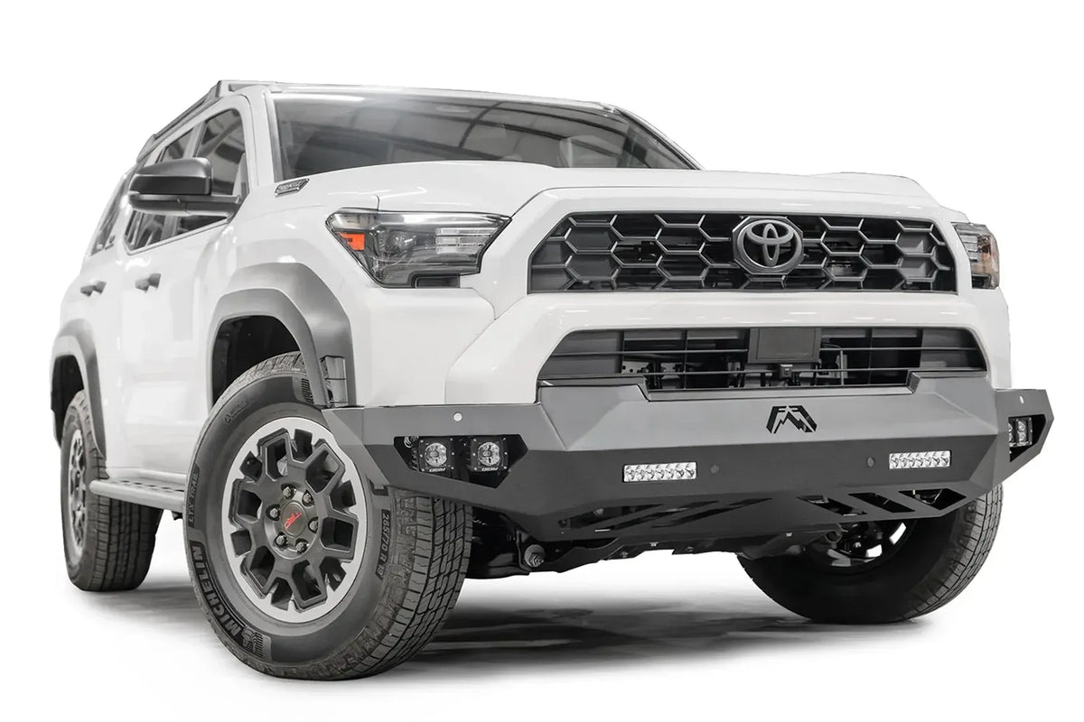 Fab Fours Vengeance front sensor bumper on a white Toyota 4Runner, passenger-side front three-quarter view, showing the angular bumper, LED light bars and skid plate