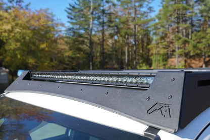 Close-up of the Fab Fours Roof Rack front fairing on a Toyota 4Runner, showing the integrated LED light bar, Fab Fours logo cutout and textured black finish