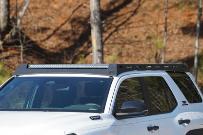 Fab Fours Roof Rack on a white Toyota 4Runner TRD Off-Road outdoors, driver-side profile, showing the low-profile rack with an LED light bar set into the front fairing