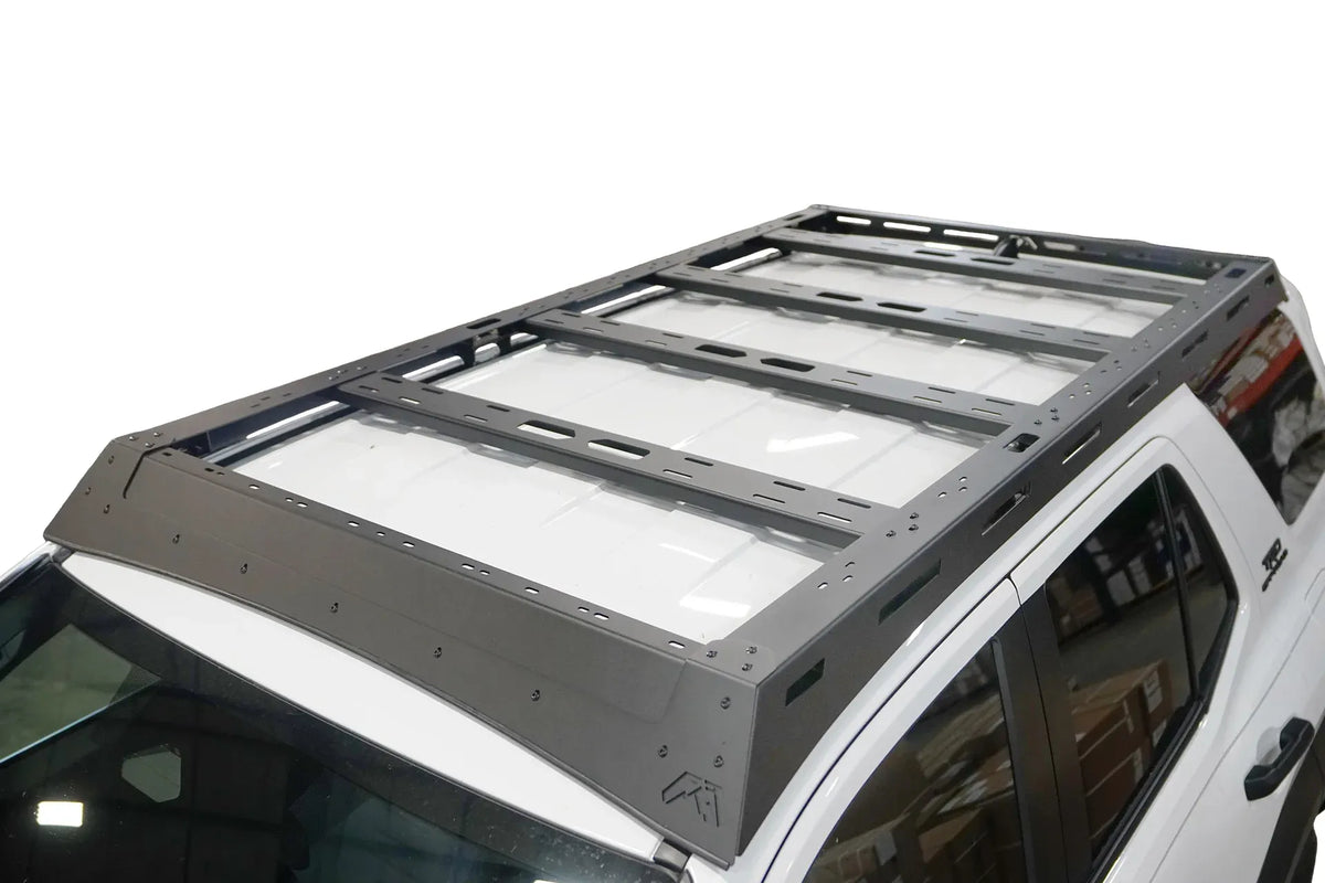 Fab Fours Roof Rack on a white Toyota 4Runner, elevated driver-side view, showing the black wind fairing with Fab Fours logo, slotted side rails and four cross-members across the roof