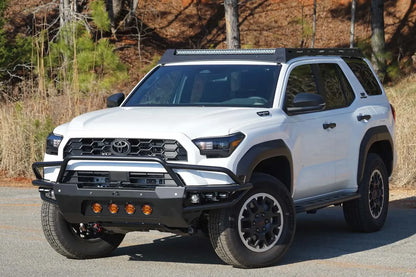 Fab Fours Roof Rack on a white Toyota 4Runner outdoors, front driver-side view, with an LED light bar in the front fairing and a black front bumper with amber lights