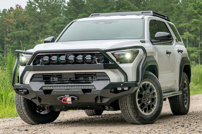 Fab Fours Matrix front winch bumper with full guard on a white Toyota 4Runner on a gravel road, driver-side front three-quarter view, showing the full guard, light bar and winch with red hook