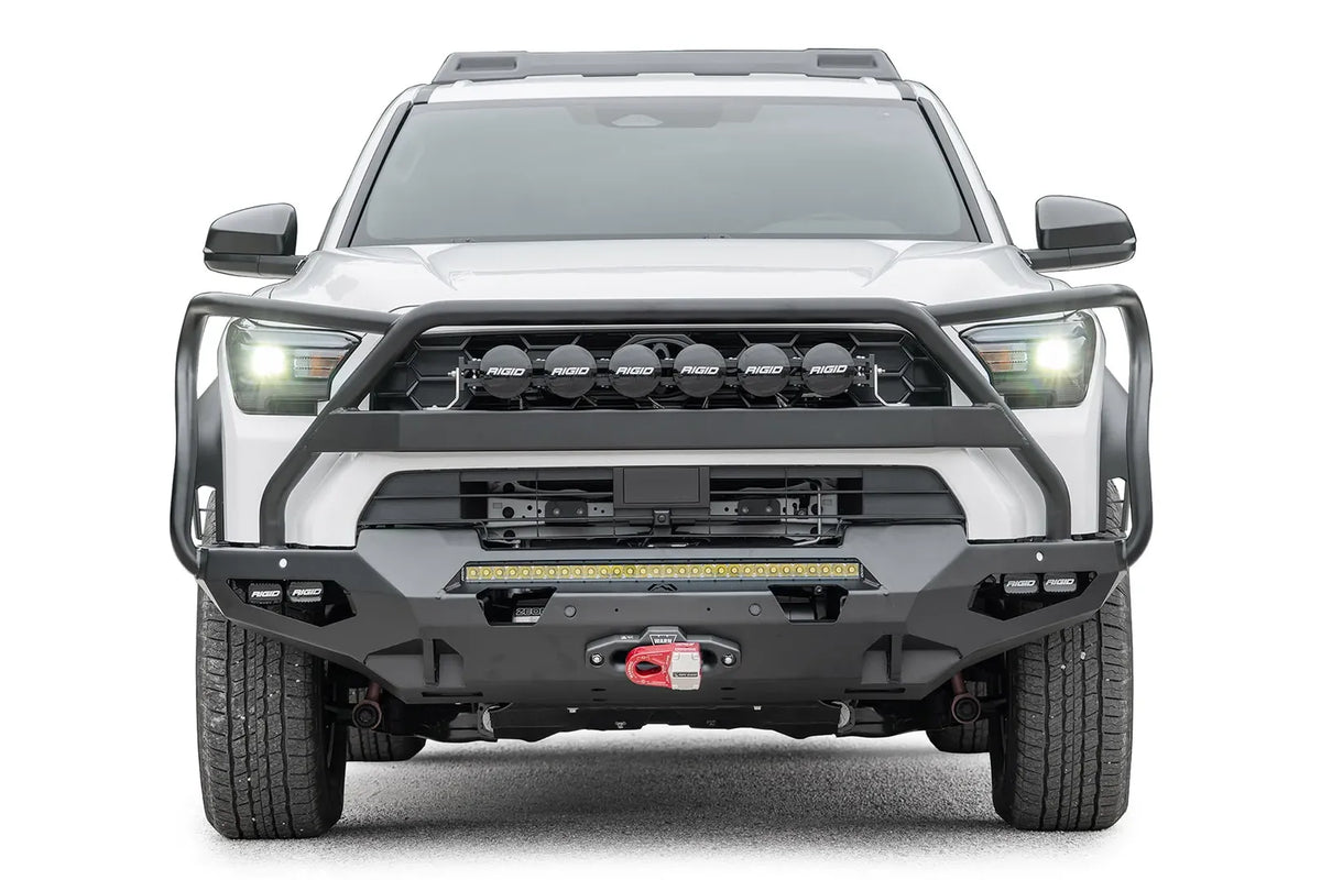 Fab Fours Matrix front winch bumper with full guard on a white Toyota 4Runner, straight-on front view, showing the full guard with light mounts, LED light bar and winch