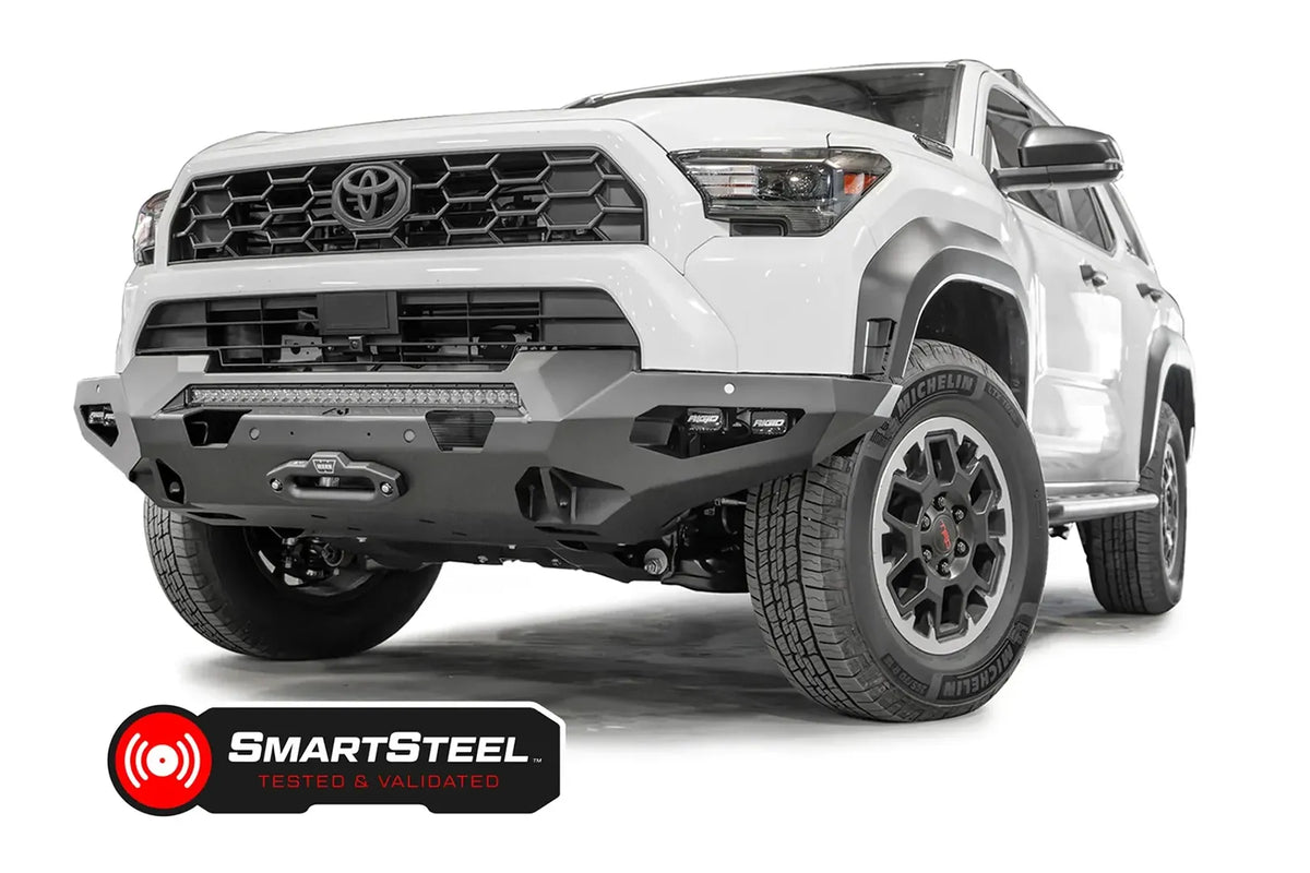 Fab Fours Matrix front winch bumper on a white Toyota 4Runner, driver-side front three-quarter view, showing the full-width bumper, LED light bar and winch fairlead