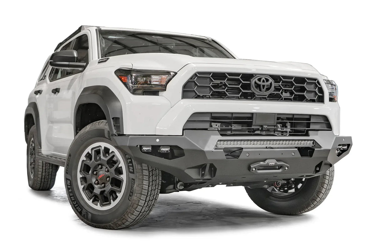 Fab Fours Matrix front winch bumper on a white Toyota 4Runner, passenger-side front three-quarter view, showing the bumper, LED light bar and winch fairlead