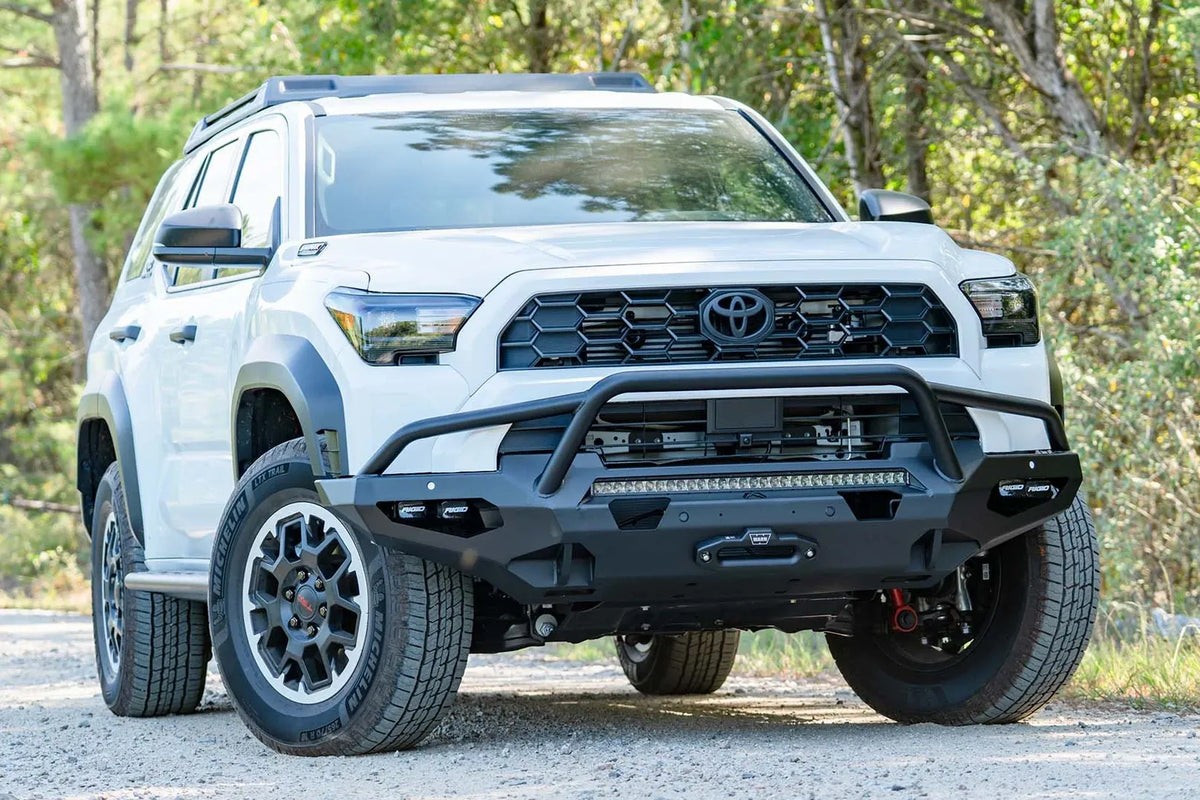 Fab Fours Matrix front winch bumper with pre-runner guard on a white Toyota 4Runner on a gravel road, passenger-side front three-quarter view, showing the tube hoop and LED light bar