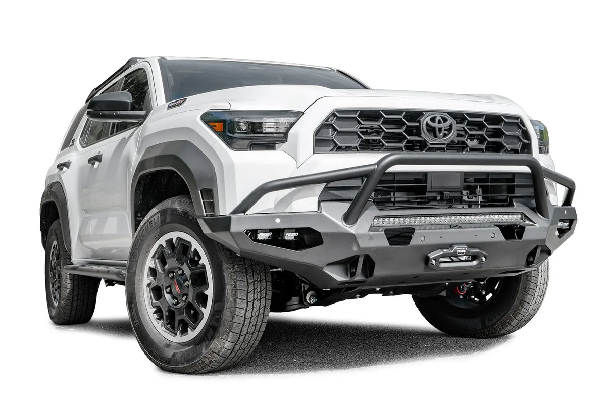 Fab Fours Matrix front winch bumper with pre-runner guard on a white Toyota 4Runner, passenger-side front three-quarter view, showing the tube hoop, LED light bar and winch