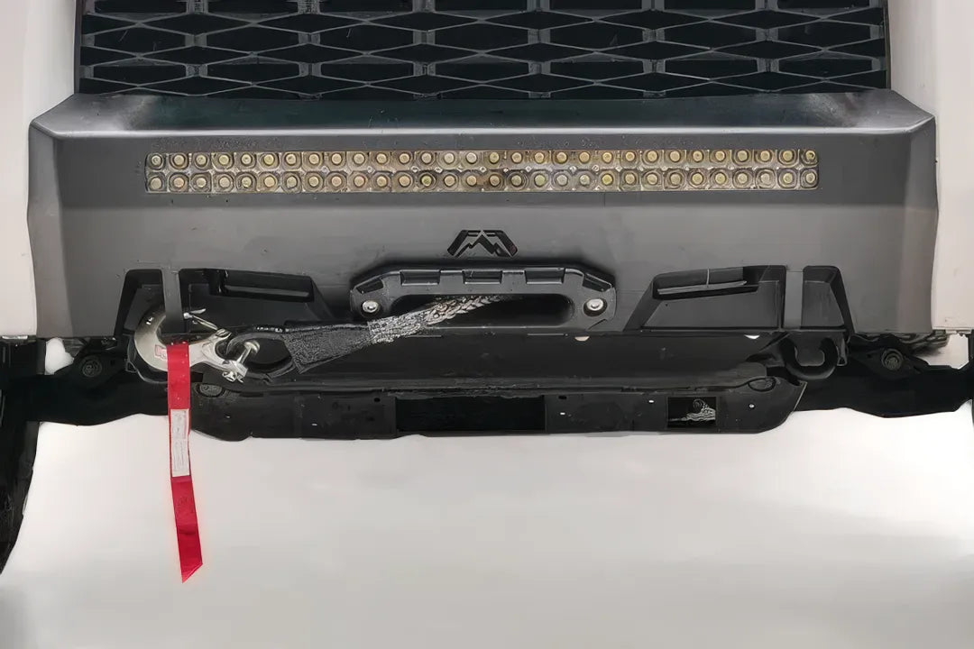 Fab Fours Hidden Winch Mount on a white Toyota 4Runner, close-up of the lower front, showing the winch fairlead, LED light bar and red winch strap