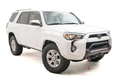 Fab Fours Hidden Winch Mount with low pre-runner guard on a white Toyota 4Runner, front three-quarter view from the passenger side, showing the pre-runner hoop, LED light bar and winch line