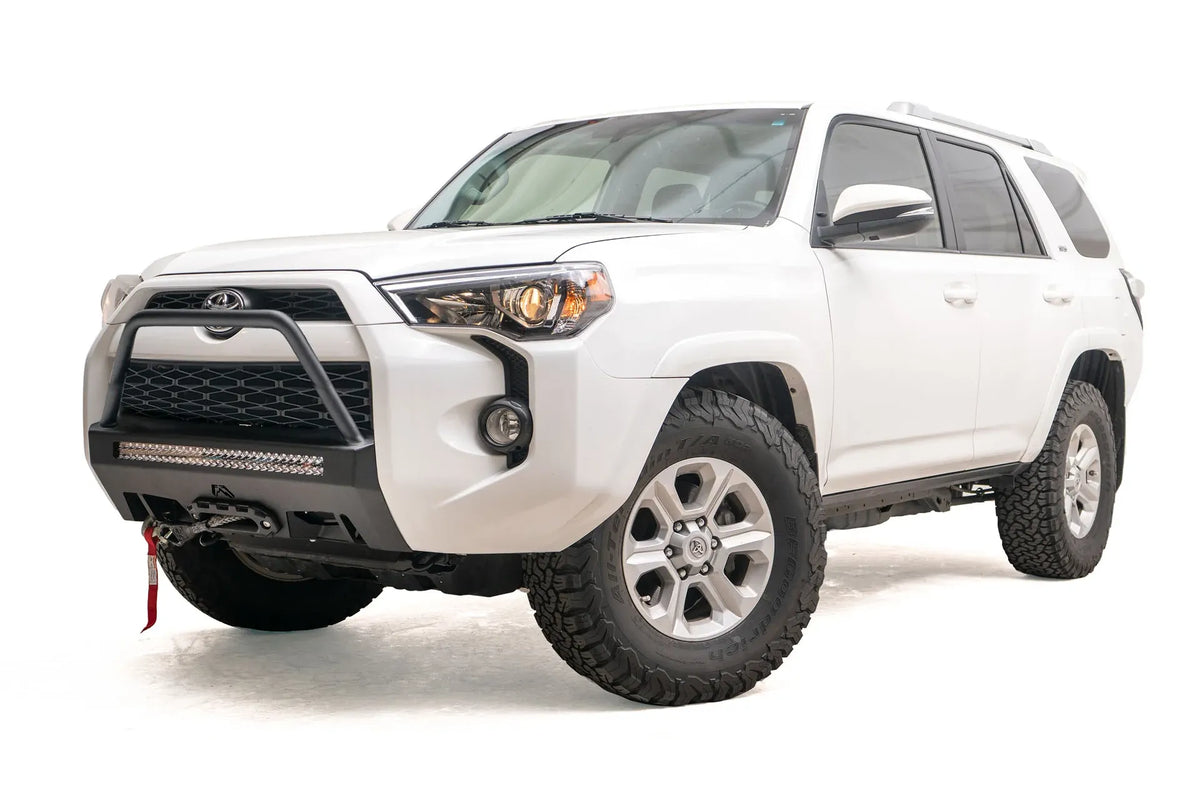 Fab Fours Hidden Winch Mount with high pre-runner guard on a white Toyota 4Runner, front three-quarter view from the driver side, showing the high pre-runner hoop, LED light bar and red winch strap