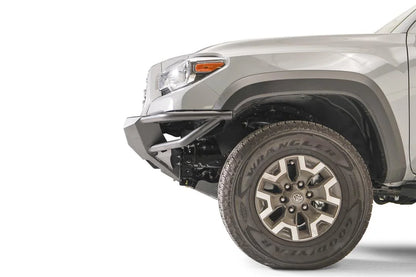 Fab Fours Hybrid front bumper on a silver Toyota Tacoma, close-up of the front corner from the side, showing the bumper end cap, tube wing and wheel clearance
