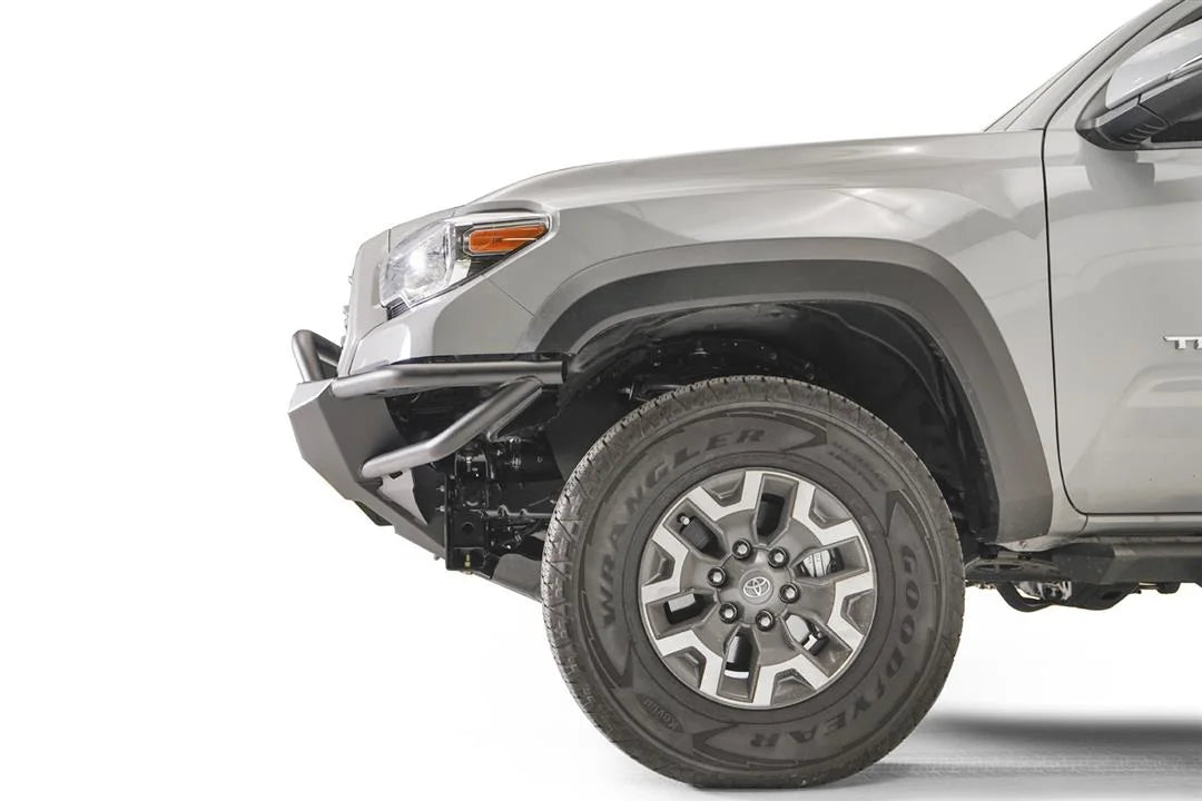 Fab Fours Hybrid front bumper with pre-runner guard on a silver Toyota Tacoma, close-up of the front corner from the side, showing the pre-runner hoop, the bumper end cap, tube wing and wheel clearance