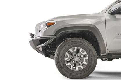 Fab Fours Hybrid front bumper with pre-runner guard on a silver Toyota Tacoma, close-up of the front corner from the side, showing the pre-runner hoop, the bumper end cap, tube wing and wheel clearance