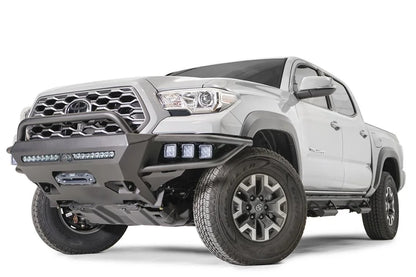 Fab Fours Hybrid front bumper with pre-runner guard on a silver Toyota Tacoma, front three-quarter view from the driver side, showing the pre-runner hoop, pod lights, LED light bar and winch opening