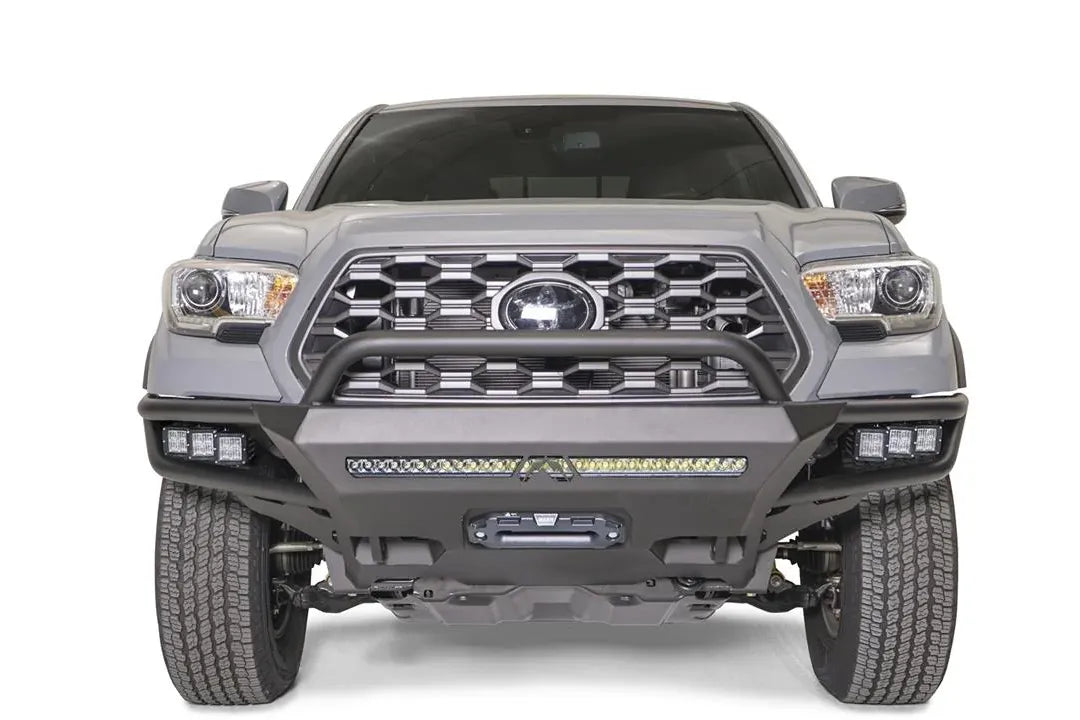 Fab Fours Hybrid front bumper with pre-runner guard on a silver Toyota Tacoma, front view, showing the pre-runner hoop, the LED light bar, cube lights and centre winch opening