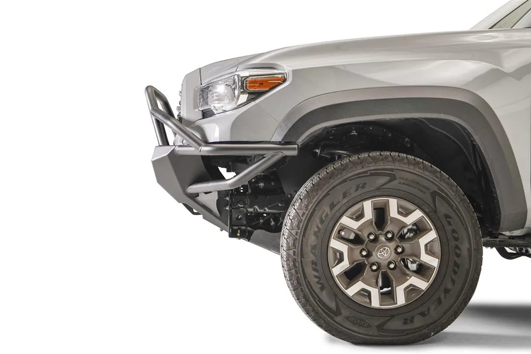 Fab Fours Hybrid front bumper with full guard on a silver Toyota Tacoma, close-up of the front corner from the side, showing the full grille guard, the bumper end cap, tube wing and wheel clearance