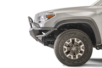 Fab Fours Hybrid front bumper with full guard on a silver Toyota Tacoma, close-up of the front corner from the side, showing the full grille guard, the bumper end cap, tube wing and wheel clearance