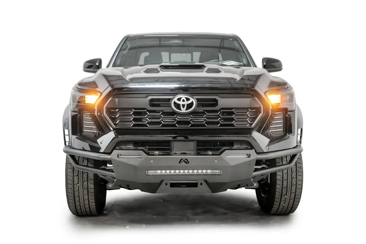 Fab Fours Hybrid front bumper on a black Toyota Tacoma, front view, showing the tube wings, LED light bar and centre winch plate
