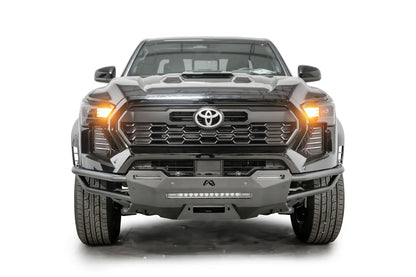 Fab Fours Hybrid front bumper on a black Toyota Tacoma, front view, showing the tube wings, LED light bar and centre winch plate