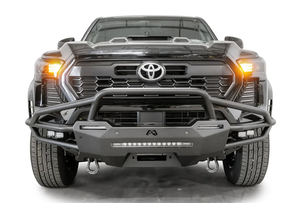 Fab Fours Hybrid front bumper with pre-runner guard on a black Toyota Tacoma, front view, showing the pre-runner hoop, LED light bar and D-ring shackles