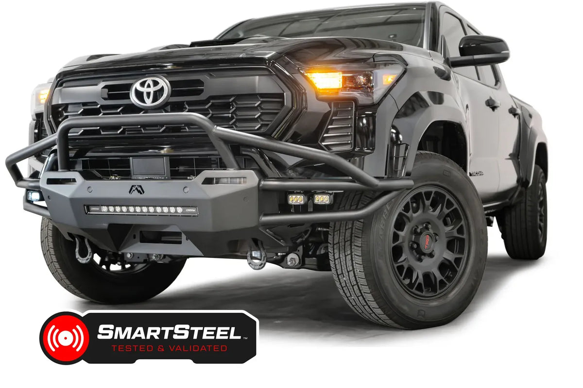 Fab Fours Hybrid front bumper with pre-runner guard on a black Toyota Tacoma, front three-quarter view from the passenger side, showing the pre-runner hoop, LED light bar and cube lights