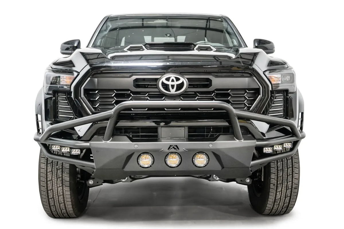 Fab Fours Ultra Light front bumper with pre-runner guard on a black Toyota Tacoma, front view, showing the pre-runner hoop, three round lights and cube lights