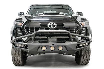 Fab Fours Ultra Light front bumper with pre-runner guard on a black Toyota Tacoma, front view, showing the pre-runner hoop, three round lights and cube lights