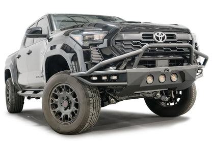 Fab Fours Ultra Light front bumper with pre-runner guard on a black Toyota Tacoma, front three-quarter view from the passenger side, showing the pre-runner hoop, tube wings and round lights