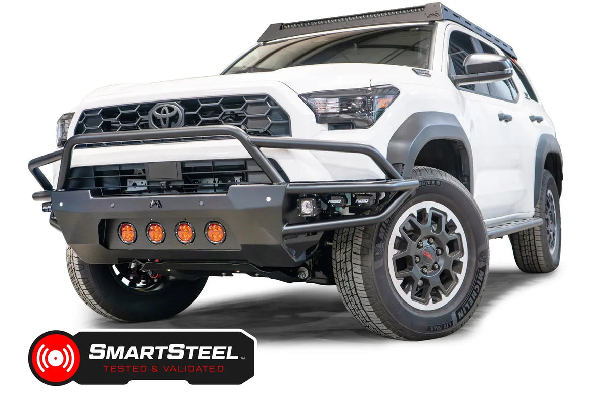 Fab Fours Ultra Light Front Bumper with guard on a white 2025 Toyota 4Runner, front driver-side view, showing the tubular guard, four amber round lights, RIGID cube lights in the wings and the SmartSteel Tested and Validated badge