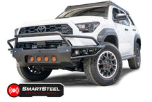 Fab Fours Ultra Light Front Bumper with guard on a white 2025 Toyota 4Runner, front driver-side view, showing the tubular guard, four amber round lights, RIGID cube lights in the wings and the SmartSteel Tested and Validated badge