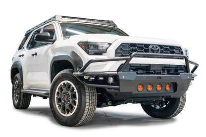 Fab Fours Ultra Light Front Bumper with guard on a white 2025 Toyota 4Runner, front passenger-side view, with the tubular guard over the grille, amber round lights and side-mounted RIGID cube lights