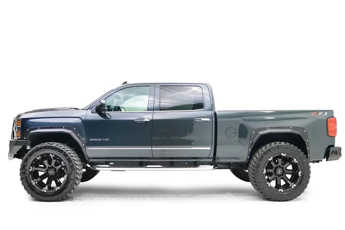 Fab Fours Open Fender Flares on a dark blue Chevrolet 2500HD, driver-side profile view, showing the front and rear open fender flares and raised wheel openings