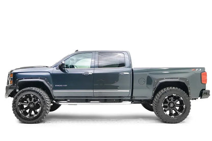 Fab Fours Open Fender Flares on a dark blue Chevrolet 2500HD, driver-side profile view, showing the front and rear open fender flares and raised wheel openings