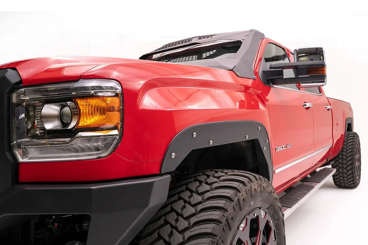 Close-up of Fab Fours open front fender flare with exposed bolts on the driver side of a red GMC Sierra 3500HD