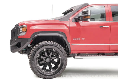Fab Fours open fender flare on the front wheel of a lifted red GMC Sierra 3500HD, driver-side profile view, with black wheel and mud-terrain tire