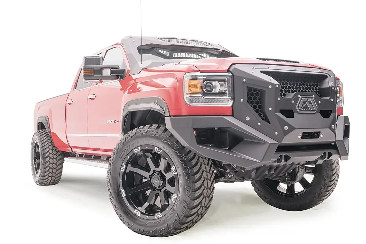 Fab Fours open fender flares on a lifted red GMC Sierra 3500HD, passenger-side front three-quarter view, with Fab Fours Grumper front bumper and cab roof visor
