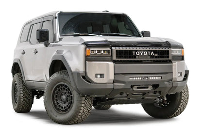 Fab Fours Hidden Winch Mount on a silver Toyota Land Cruiser, front three-quarter view from the passenger side, showing the low-profile winch plate, LED light bar and fairlead
