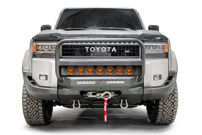 Fab Fours Hidden Winch Mount with pre-runner guard on a silver Toyota Land Cruiser, front view, showing the pre-runner guard, amber light bar, winch fairlead and D-ring shackles