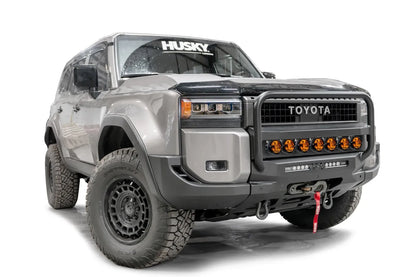 Fab Fours Hidden Winch Mount with pre-runner guard on a silver Toyota Land Cruiser, front three-quarter view from the passenger side, showing the pre-runner guard, amber light bar and winch fairlead