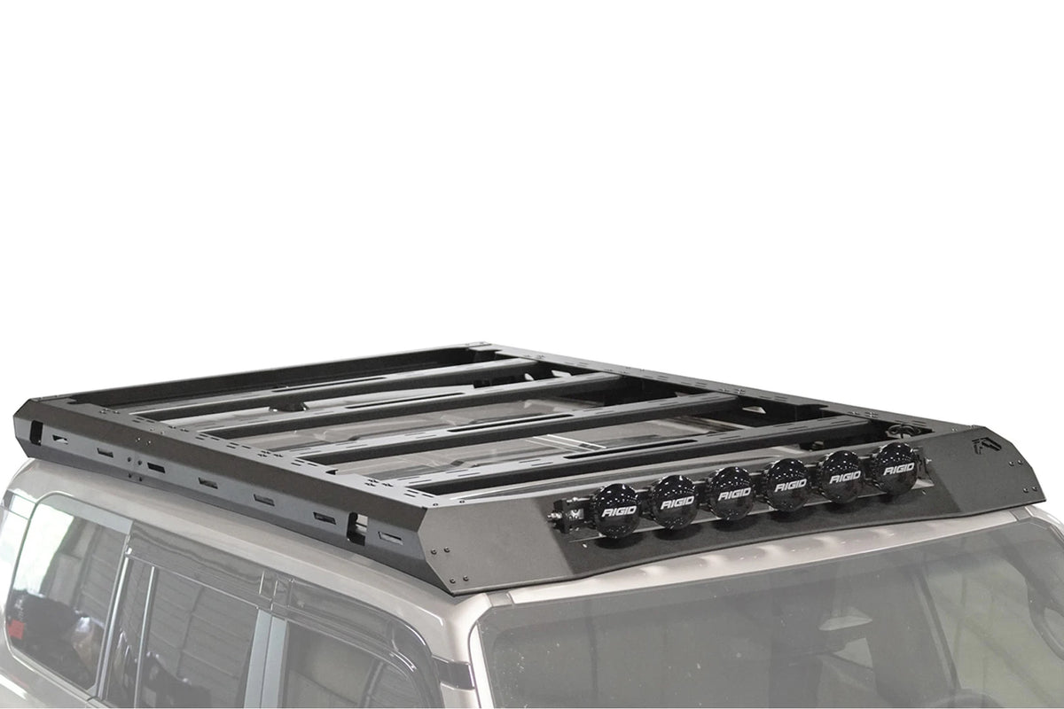 Fab Fours Roof Rack on a silver Toyota Land Cruiser roof, passenger-side view, showing the platform crossbars, slotted side rails and six RIGID lights on the wind fairing
