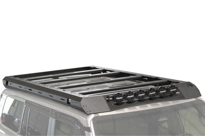 Fab Fours Roof Rack on a silver Toyota Land Cruiser roof, passenger-side view, showing the platform crossbars, slotted side rails and six RIGID lights on the wind fairing