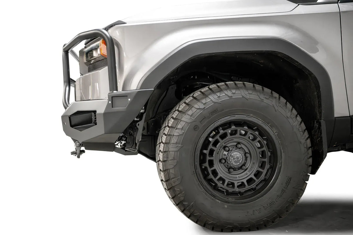 Fab Fours Matrix front bumper with full guard on a silver Toyota Land Cruiser, close-up of the front corner from the side, showing the full guard side tube, bumper end and wheel clearance